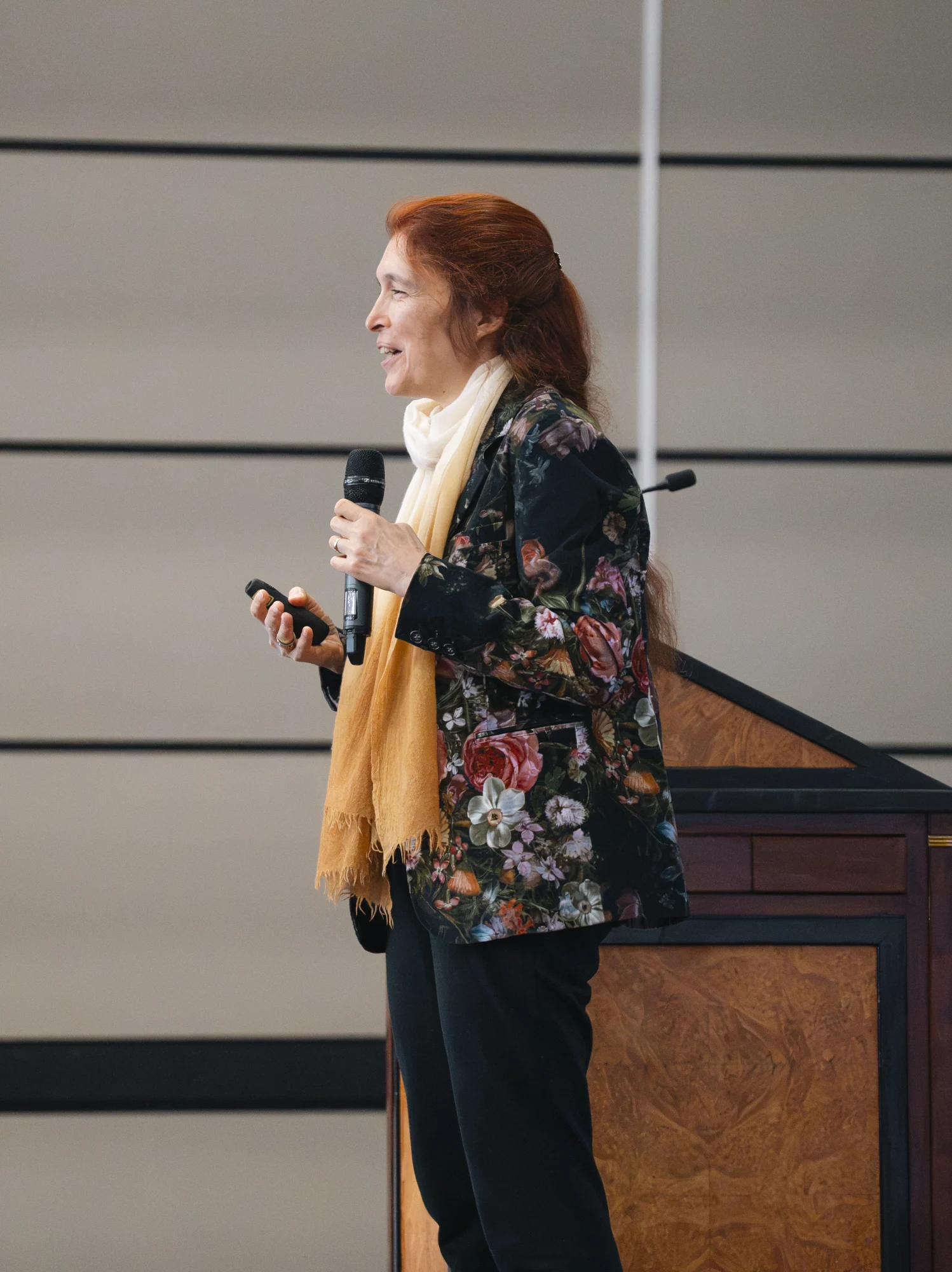 A conference presenter holding a microphone beside the lectern